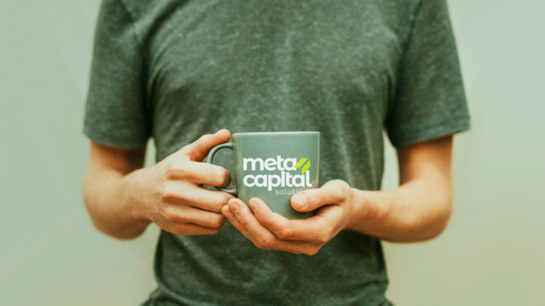 Caneca verde com a logo nas mãos de uma pessoa